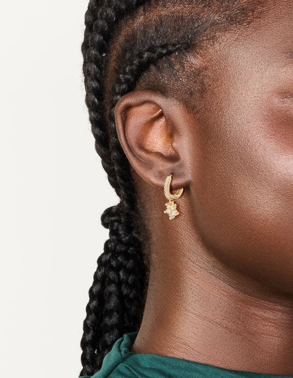 Showcasing gold plated cubic zirconia flower pendant huggie earrings in clear stone on ear view
