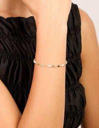 Showcasing a gold plated bracelet with green beads and pearls on wrist view - link has visual effect only