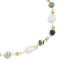 Highlighting a gold plated bracelet with green beads and pearls close up view - link has visual effect only