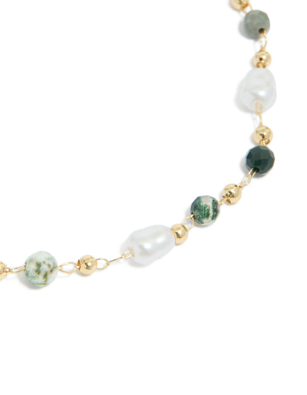 Highlighting a gold plated bracelet with green beads and pearls close up view