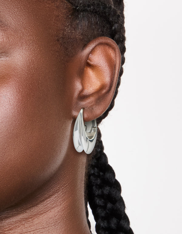 Featuring waterproof stainless steel oval concave huggie earrings in silver on ear view