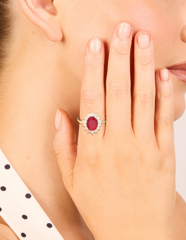 Elegant statement ring with oval cut red cubic zirconia and clear halo stones in gold plated metal on finger view