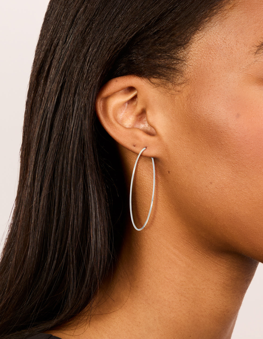 Showcasing surgical steel fine hoop earrings in 60 MM with silver finish on ear view