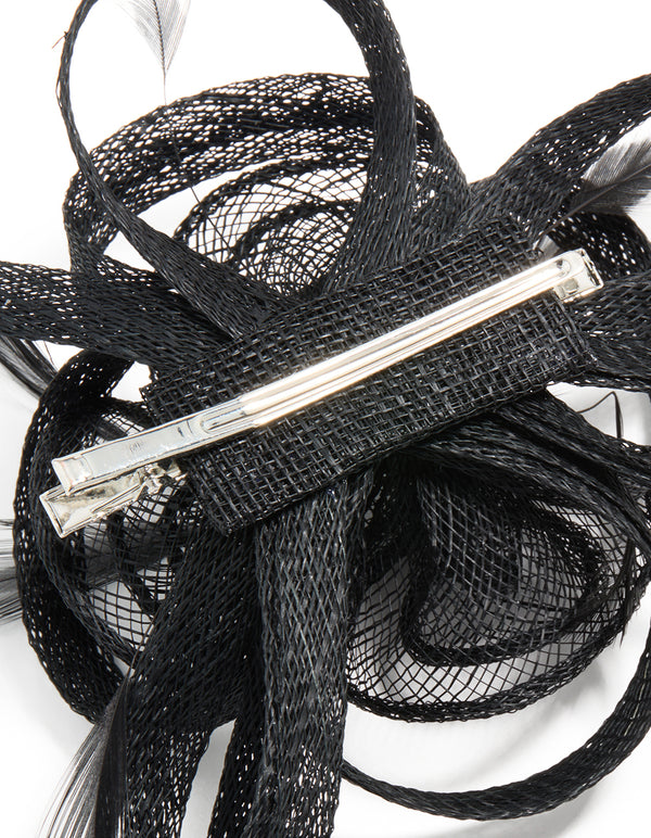 This black sinamay fabric floral hair clip features a swirl and feather design, detail view