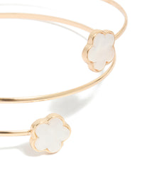 A gold small flower arm cuff with white floral details in close up view - link has visual effect only