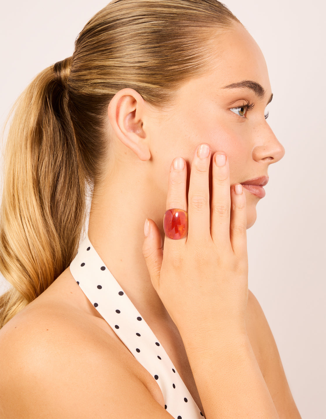 Showcasing statement acrylic rings in coral and orange with floral gold accents, 3-pack on finger view