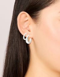 Showcasing silver plated cubic zirconia and smooth hoop earrings in a 2-pack with crystal accents on ear view - link has visual effect only
