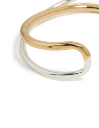 Highlighting a mixed metal open crossover wrist cuff with gold plated and silver finish in bangle form close up view - link has visual effect only