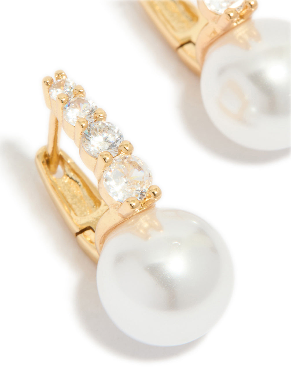 Highlighting gold plated huggie earrings showcasing cubic zirconia stones and pearl drop close up view