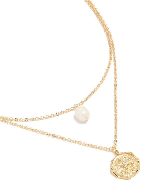 Showcasing a gold plated brass layered necklace with celestial, coin pendant, pearl and cubic zirconia accents close up view