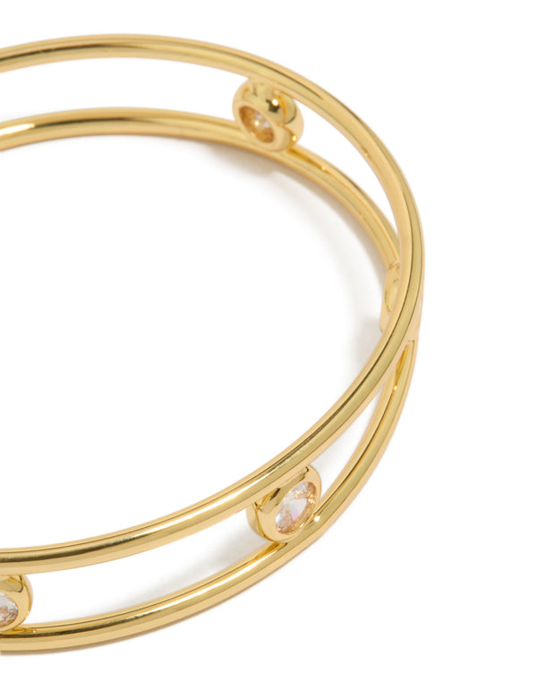 Showcasing a statement bangle in gold plated brass with bezel set cubic zirconia stones and wrist cuff styling close up view