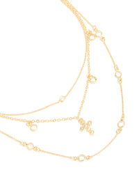 Beautifully crafted gold plated layered necklace featuring cubic zirconia bezel settings and cross pendant in statement design close up view - link has visual effect only