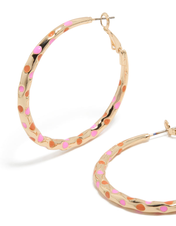 Displaying large thin hoop statement earrings with enamel dotted pattern in gold, pink, and coral close up view