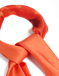 Highlighting an orange fabric scarf with double hibiscus floral print in coral, tomato, and dark orange shades, detail view - link has visual effect only