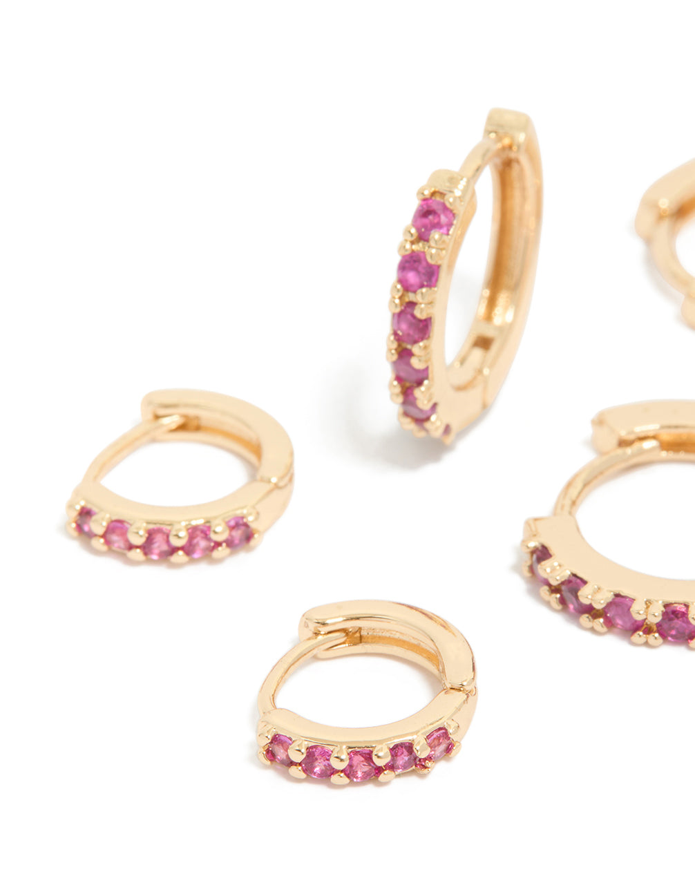 Featuring gold dark pink cubic zirconia huggie earrings in a 3-pack close up view