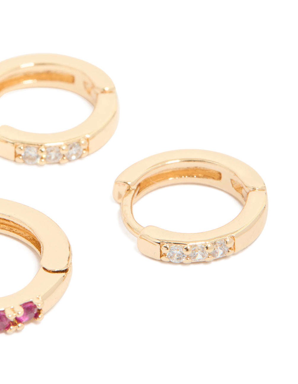 Featuring gold dark pink cubic zirconia huggie earrings in a 3-pack close up view