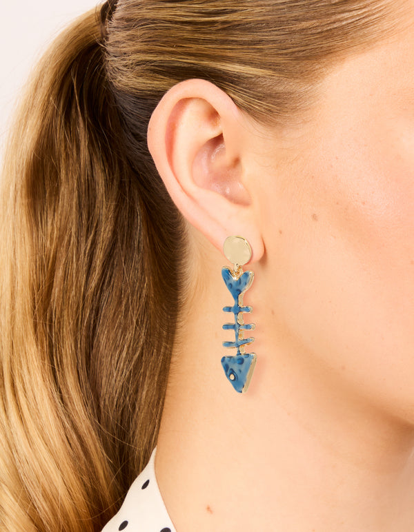 Showcasing gold blue fish skeleton drop earrings with ocean charm theme in steel on ear view