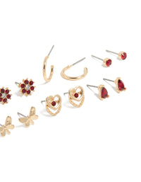Shop stud earrings in a 7-pack featuring butterfly, floral, heart, and ball accents with gold finish and red diamante details post detail view - link has visual effect only