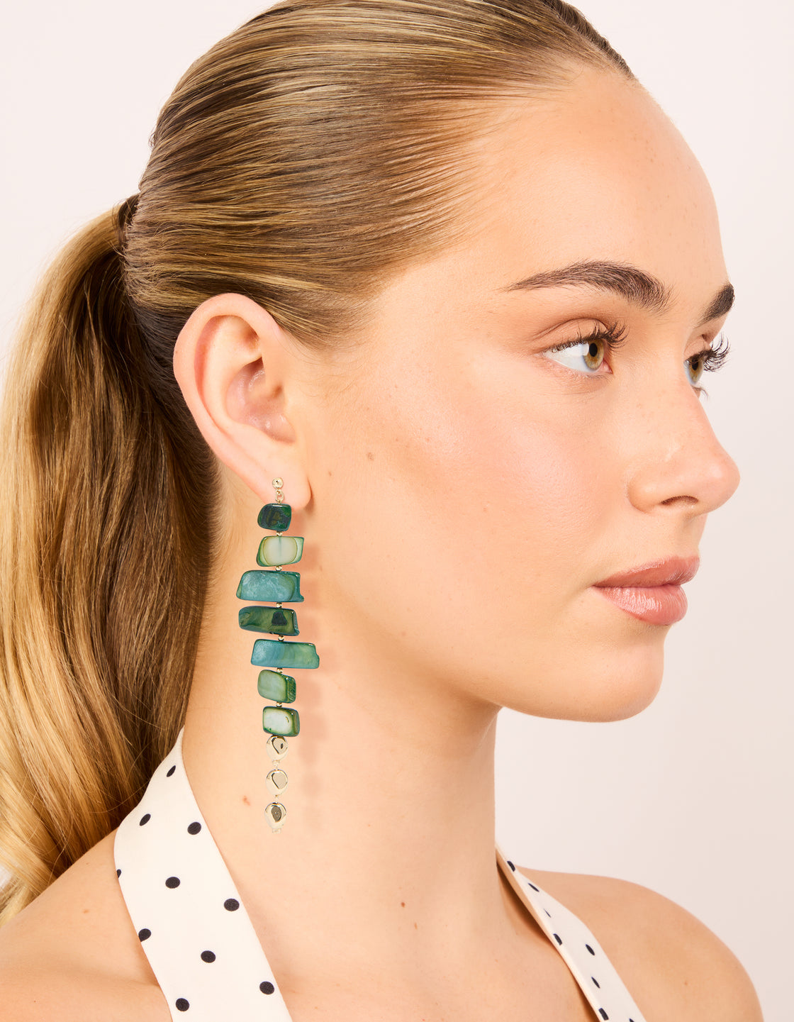 Discover dark green acrylic irregular shaped drop earrings with beads in teal, pale green, and gold on model view