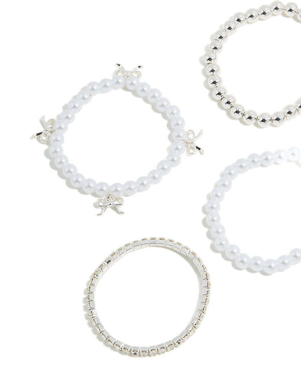 Detailed view of kids beaded stretch bracelets with bow charm accents and pearl elements in silver tones close up view