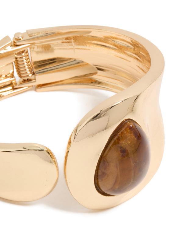 Showcasing a gold teardrop brown stone wrist cuff in statement style close up view