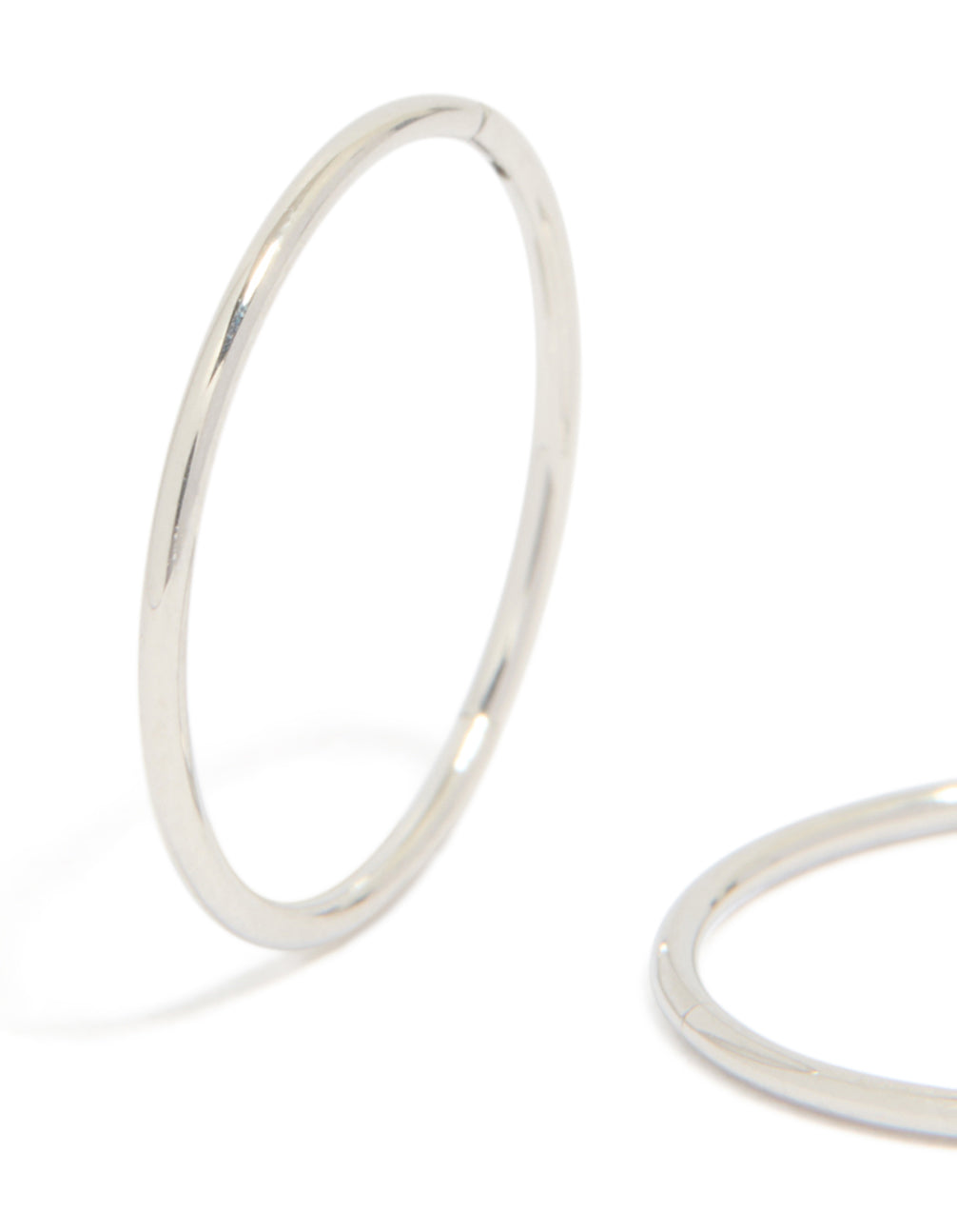 Highlighting surgical steel sleeper earrings in silver with hoop closure close up view