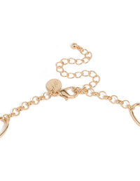 Highlighting the long beaded necklace with balls, beads, charm accents and tassel fringe in gold statement style clasp detail view - link has visual effect only