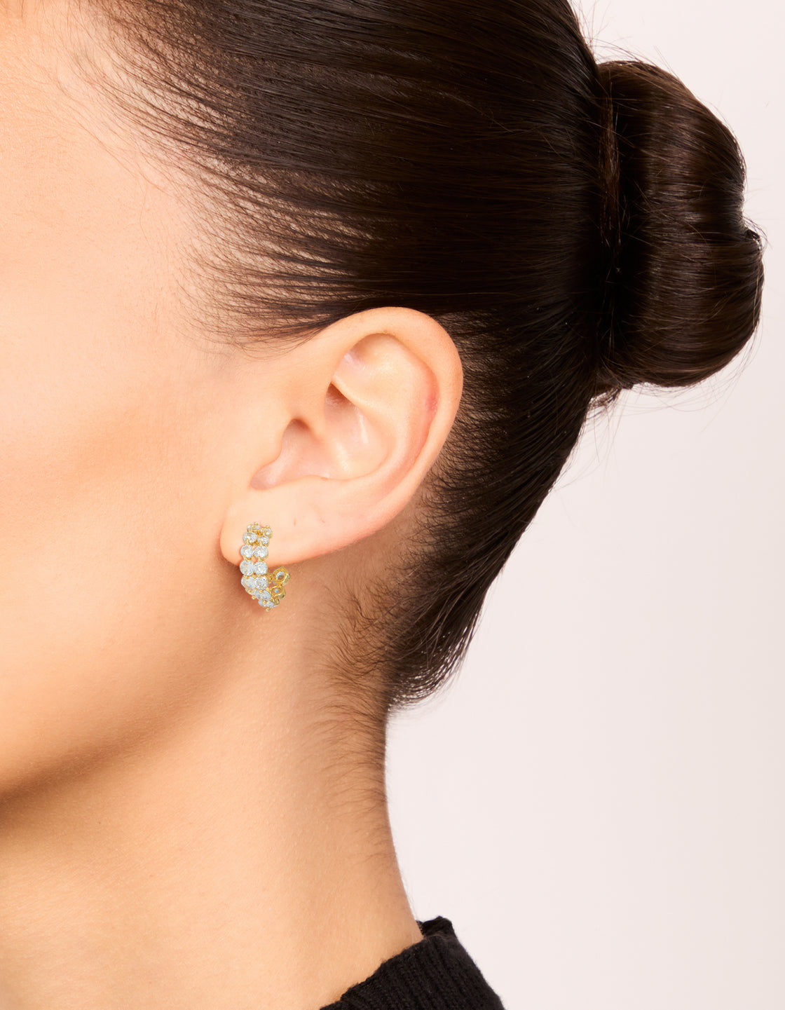 Displaying small hoop style earrings crafted from cubic zirconia and gold plated metal with double layered detail on ear view