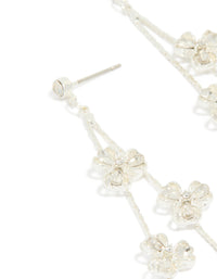 Highlighting dainty silver floral drop earrings with intricate petal detailing and clear finish close up view - link has visual effect only