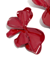 Featuring large statement stud earrings with floral petal design in red coated metal close up view - link has visual effect only