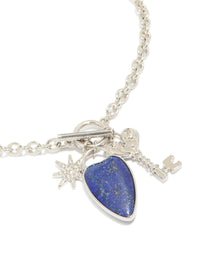 Showcasing a silver diamante and blue stone heart chunky style necklace with celestial charms featuring star pendant close up view - link has visual effect only