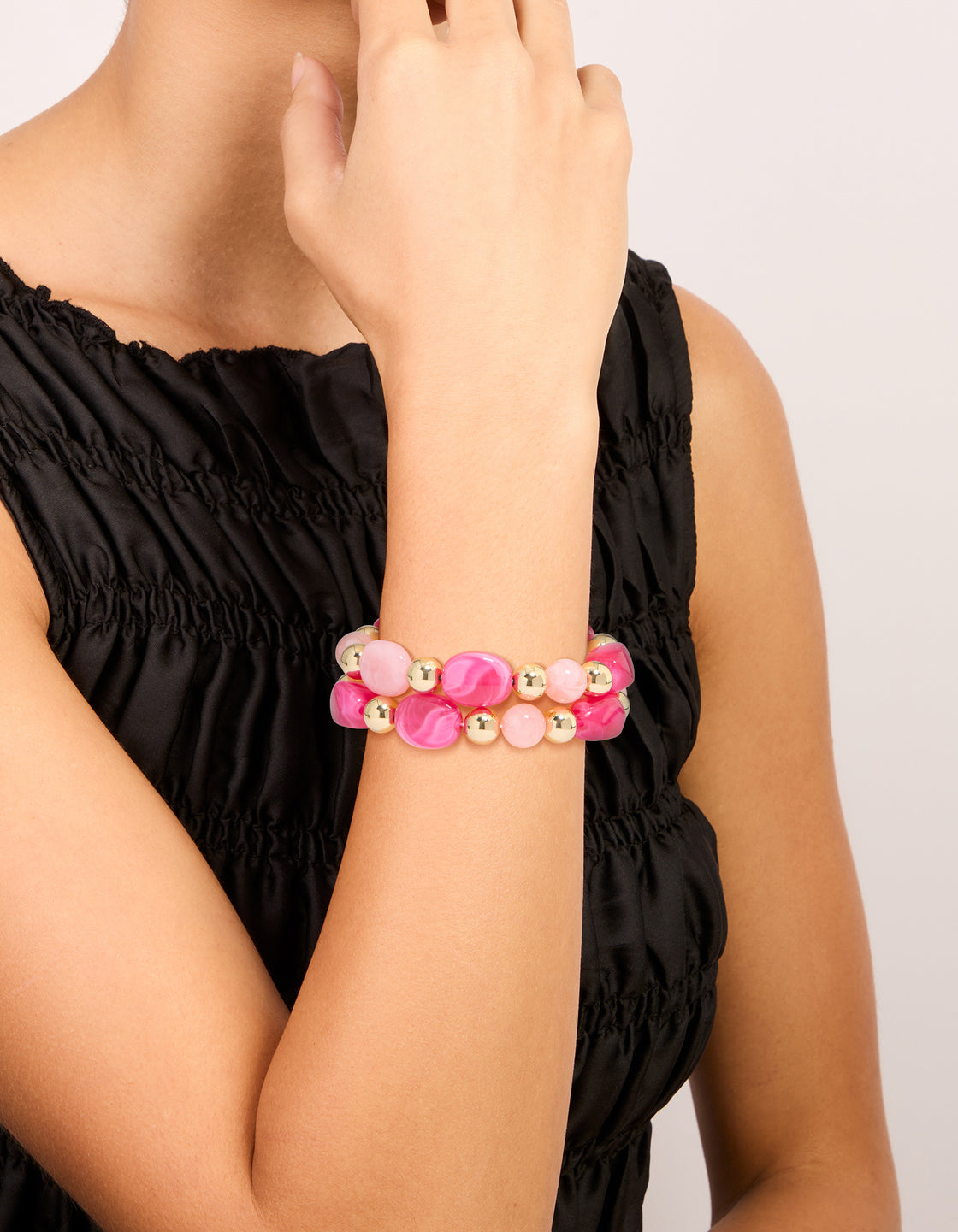 Crafted from hot pink and light pink acrylic with gold beaded stretch bracelets shown in a 2-pack on wrist view