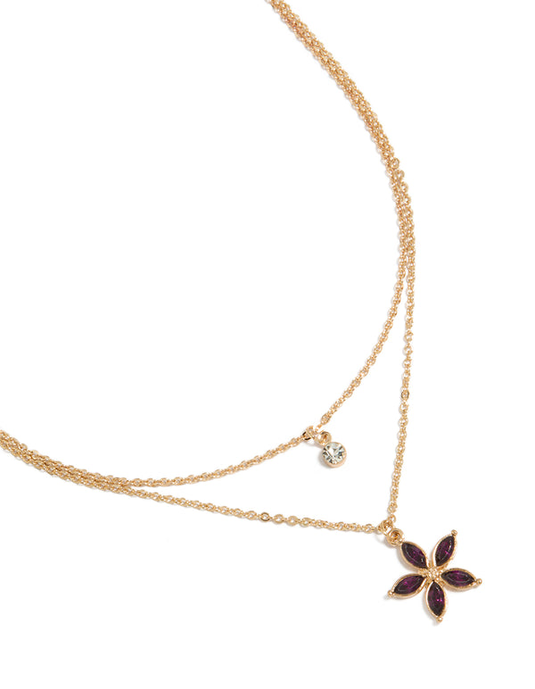 Showcasing a gold layered necklace with clear and purple diamante floral pendant close up view