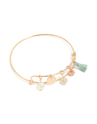 Showcasing a gold pearl, tassel, charm bangle featuring beads and disc in aquamarine, and pink front view - link has visual effect only
