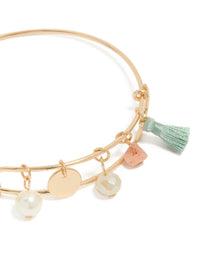 Crafted from gold, this pearl, tassel, charm bangle with beads and disc in aquamarine, and pink close up view - link has visual effect only