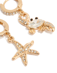 Detailed view of mismatched gold huggie earrings with ocean details and crystal embellishments close up view - link has visual effect only