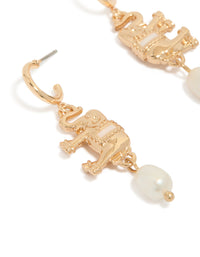 Highlighting gold hoop earrings featuring a freshwater pearl and an animal elephant charm with ivory accents close up view - link has visual effect only