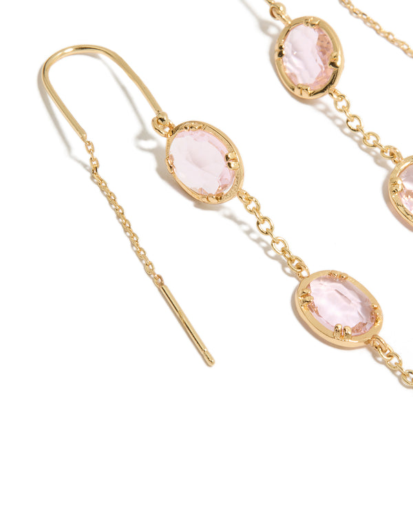 Detailed perspective of statement earrings crafted from gold plated material with oval cut pink diamantes in a thread through design close up view