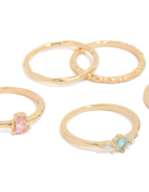 Showcasing gold plated rings with solitaire and oval stone cut cubic zirconia in pink and blue crystal close up view