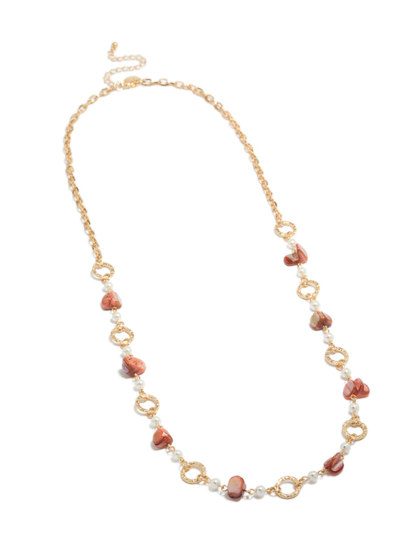 Featuring a gold open circle long statement necklace with beads and pearls in pink coral and white tones front view