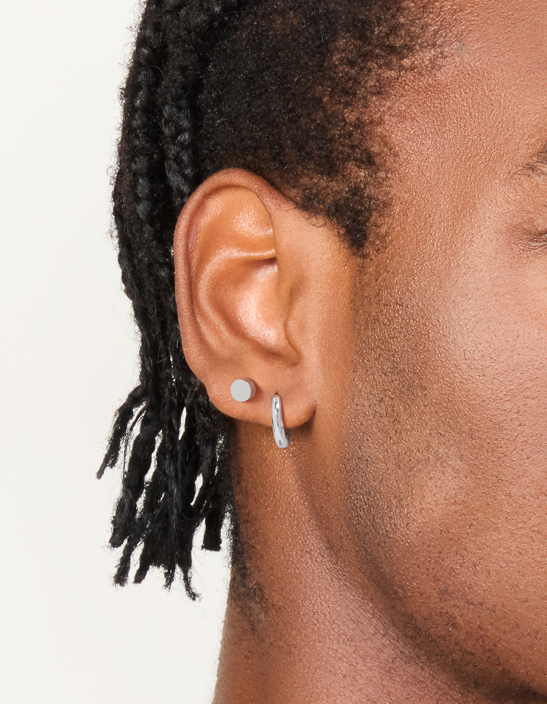 Featuring waterproof men's stainless steel flat stud and huggie earrings in a 2-pack with silver finish on ear view