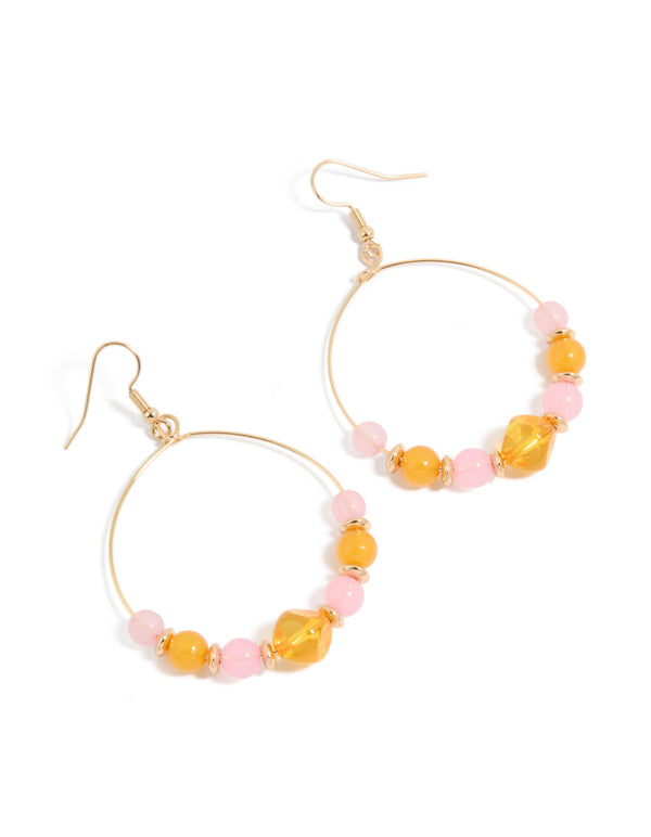 Showcasing statement drop earrings with round beads featuring textured light pink and orange details in gold front view