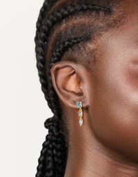 Featuring statement gold plated light blue cubic zirconia trip drop earrings in aqua on ear view - link has visual effect only