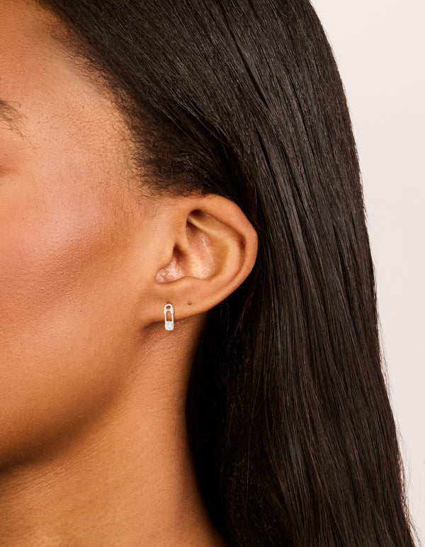 Elegant sterling silver cubic zirconia safety pin stud earrings in a statement style on ear view