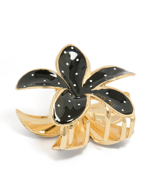 Showcasing a floral enamel polka dot patterned gold claw clip with black and white accents side view